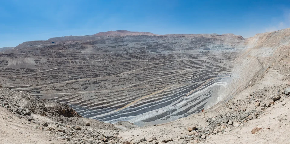 Terraced walls of the Chuquicamata copper mine in Chile beneath a clear blue sky